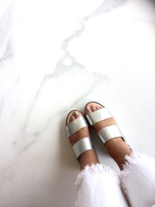 Marble floor with paid of silver shoes and white bell bottoms in silver toe polished feet.
