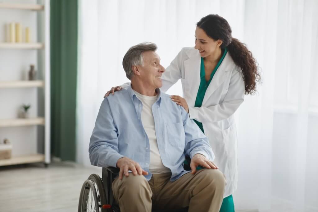 Portrait of happy senior man in wheelchair and his female nurse at retirement home