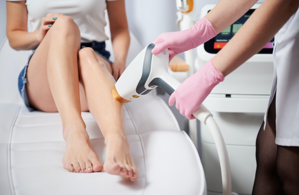 Woman receiving laser hair removal treatment in beauty salon.