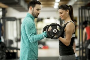 Young woman with personal trainer in gym